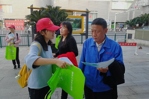 图为志愿者向行人发放宣传单和环保袋 阮双蓉 摄.jpg